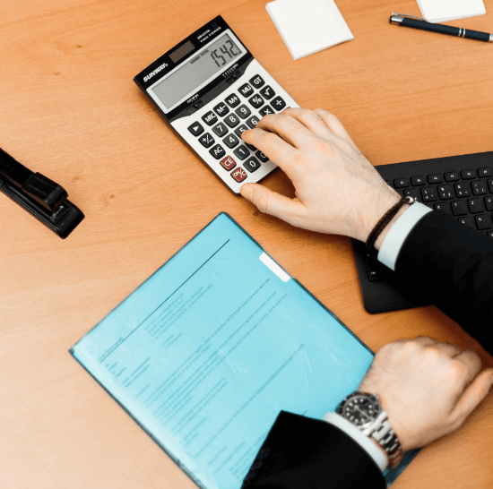 person-using-calculator-on-brown-wooden-surface-2058138